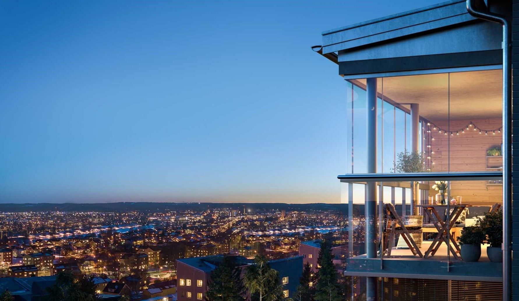 Glasad balkong med utsikt över en stadslandskap i kvällsljus, med bord och stolar samt dekorativa ljusslingor