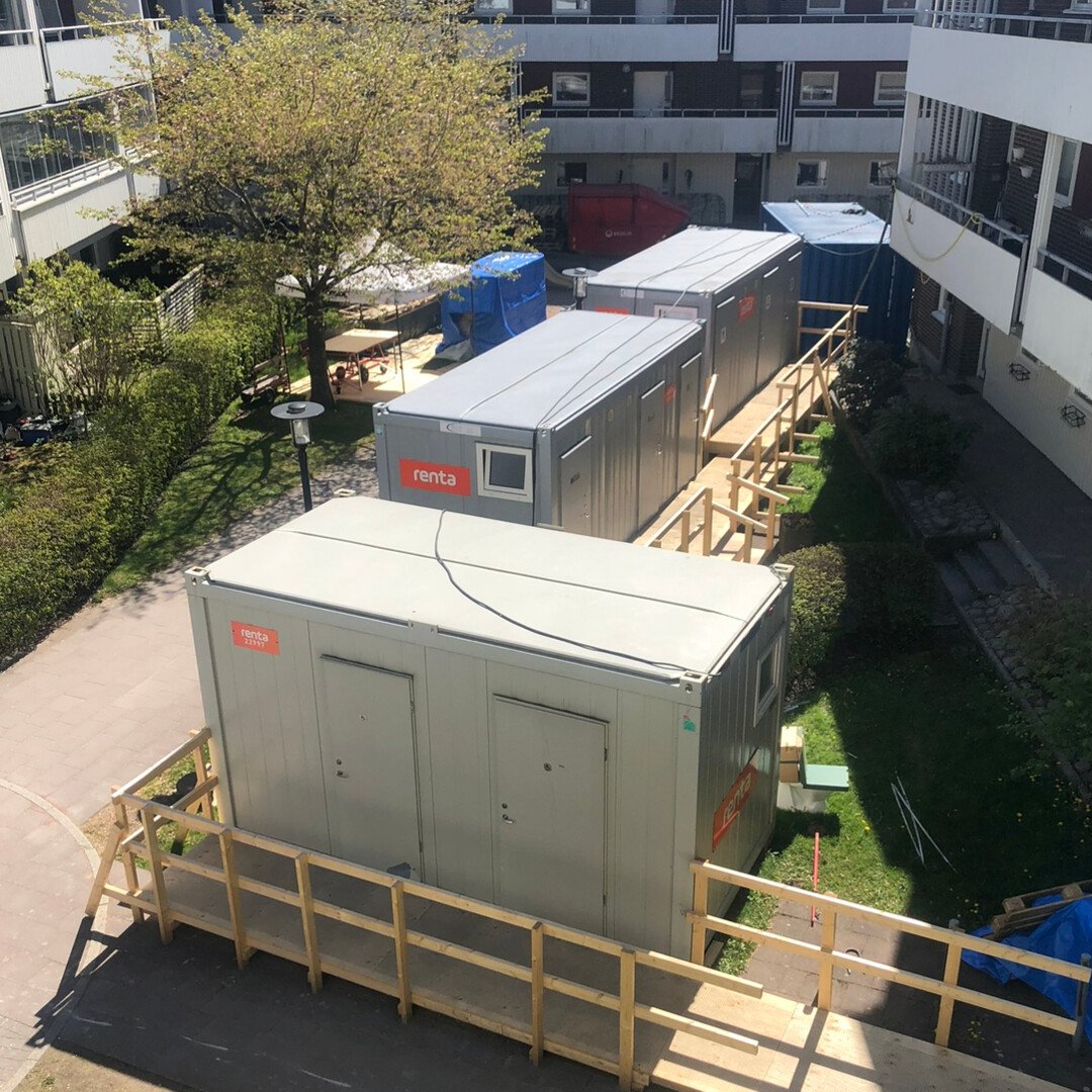 Tillfälliga evakueringsbodar uppställda i en innergård med omgivande byggnader och träd