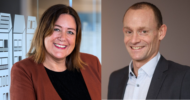 Två personer står bredvid varandra; en person i brun kavaj med svart topp till vänster och en person i mörk kostym med vit skjorta och slips till höger. Bakgrunden består av kontorsmiljö och enfärgad vägg