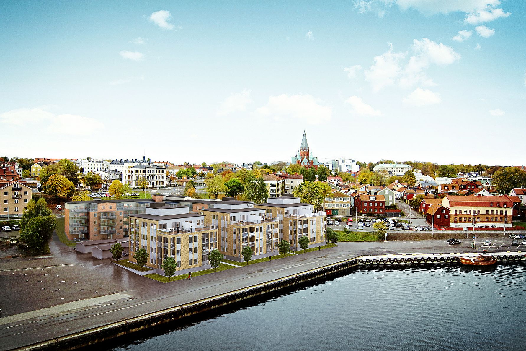 Flygbild över en svensk stad med moderna lägenhetsbyggnader nära en kaj, omgivna av äldre byggnader och grönska