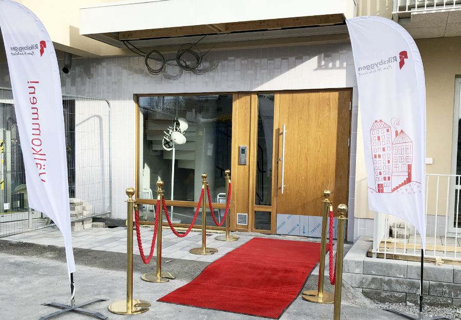 Entré med röd matta, avspärrningar med röda rep samt två vita flaggor med tryck, placerade vid sidan av dörren