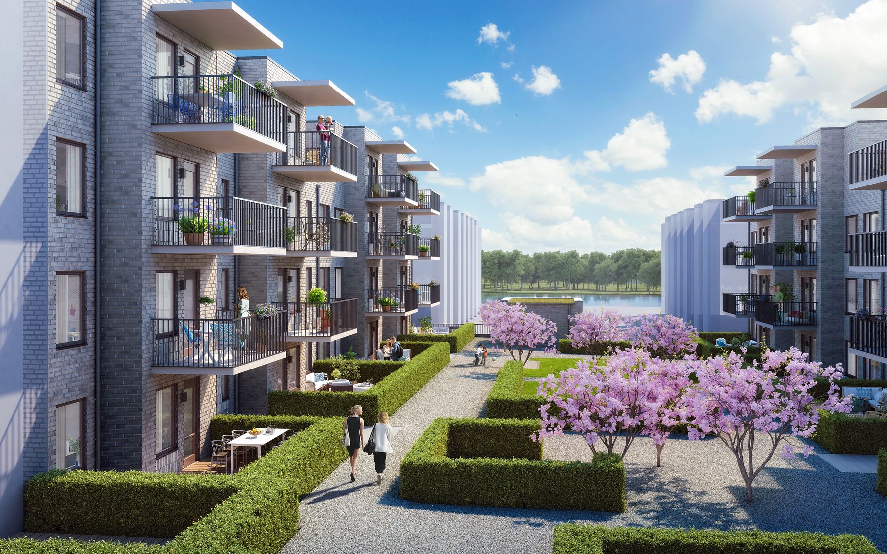 Modernt bostadsområde med flerfamiljshus, balkonger, välskötta häckar, blommande träd och gångväg i solsken