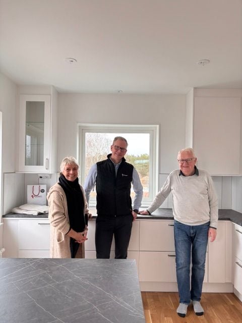 Tre personer står i ett modernt kök