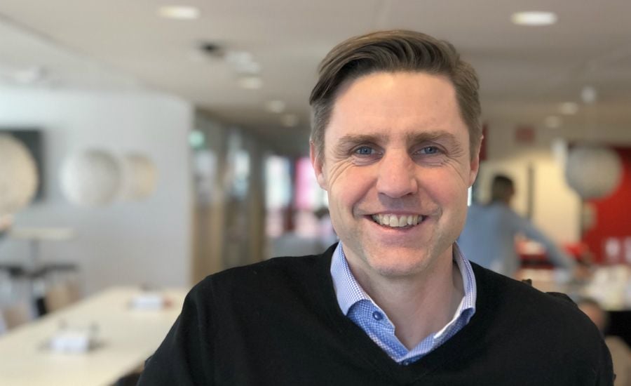 En person i en kontorsmiljö med suddig bakgrund som visar bord, stolar och dekorationer på väggarna
