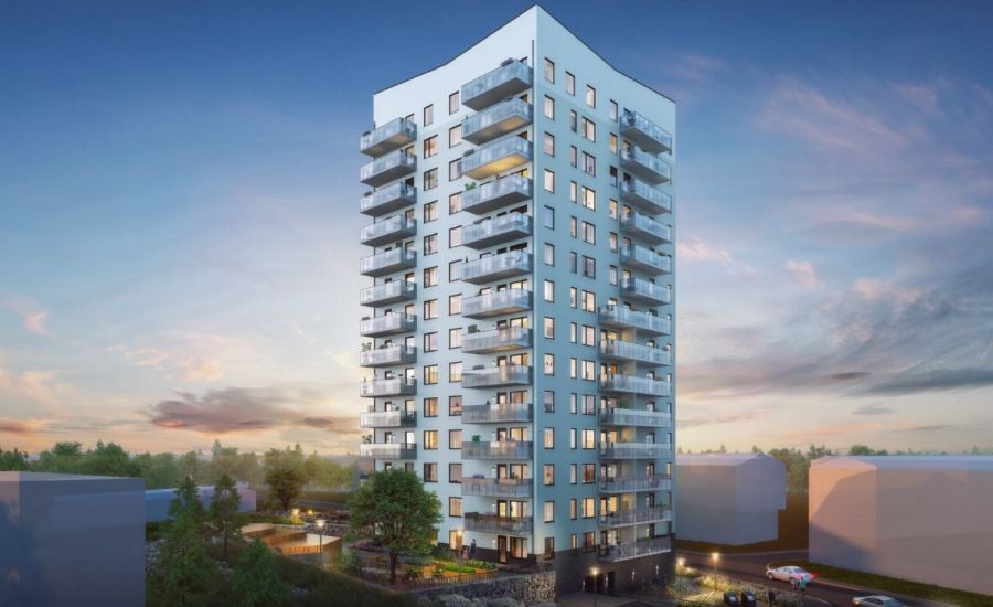 Höghus i modern arkitektur med flera balkonger, omgiven av grönska och byggnader, mot en bakgrund av solnedgång
