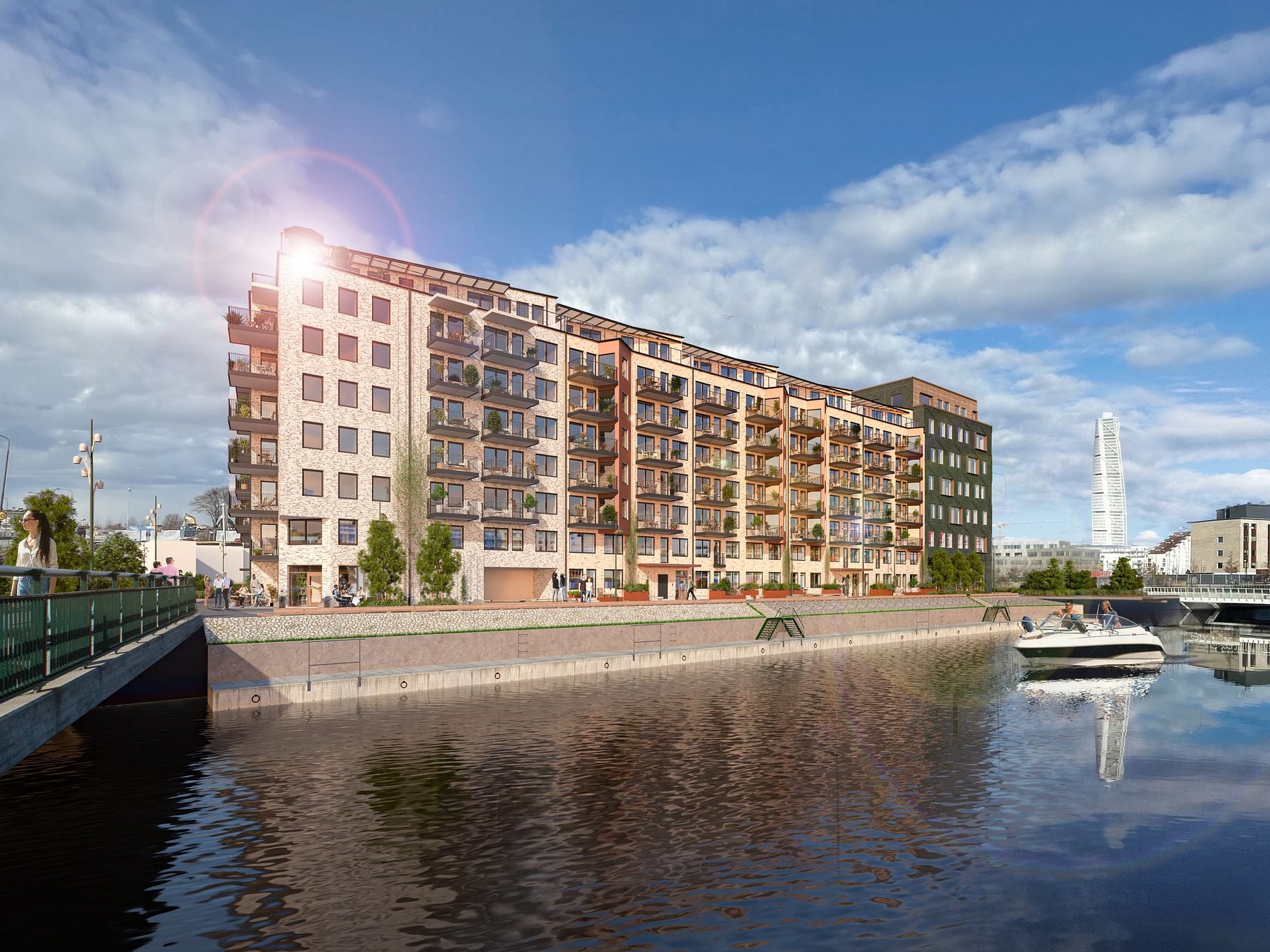 Nybyggda flerbostadshus vid vattnet under en klarblå himmel, med en båt på kanalen och Turning Torso synlig i bakgrunden
