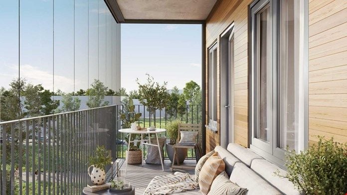 Modern balkong med trämöbler, krukväxter och en beige soffa; glasväggar och grönska i bakgrunden