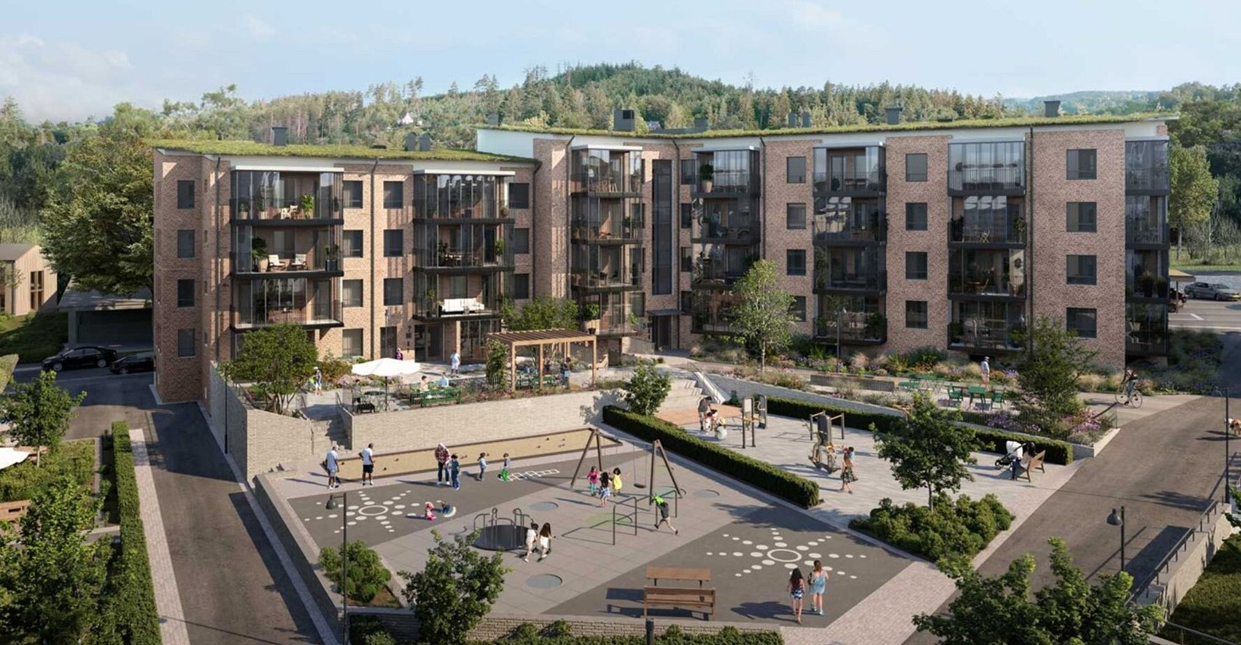 Bostadsområde med moderna flerfamiljshus i tegel, en lekplats och grönområden i förgrunden, omgivet av träd och natur