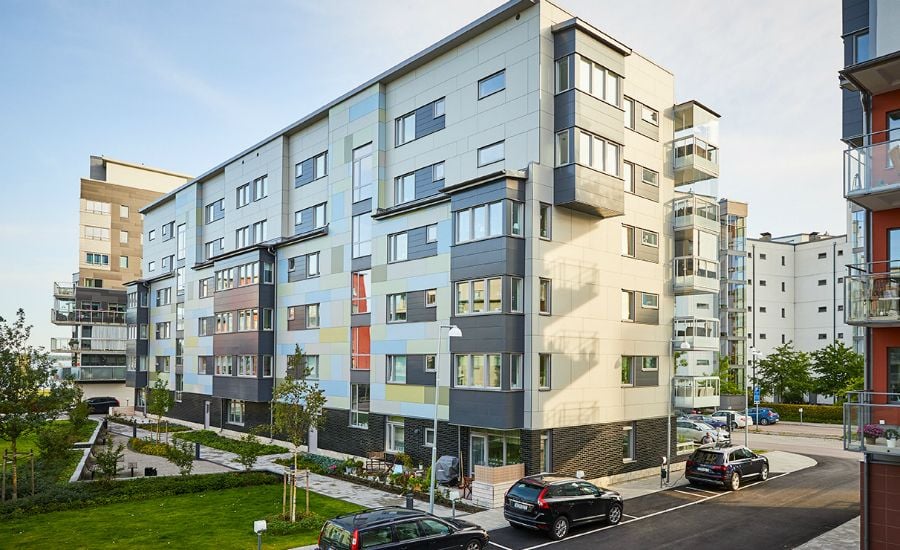 Modern lägenhetsbyggnader med flera våningar, parkeringsplatser och grönområden i ett bostadsområde