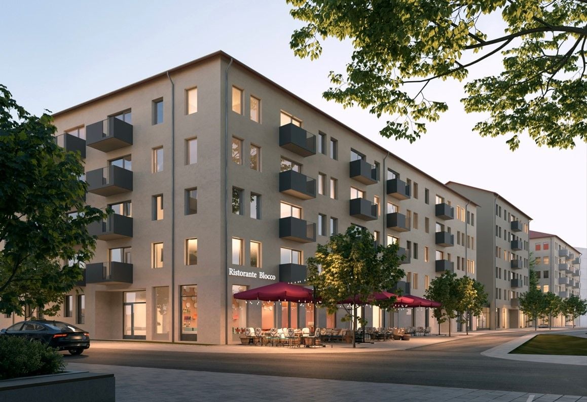 Bostadsbyggnad med flera våningar och balkonger, utomhusservering med röda markiser, omgiven av trottoarer och träd