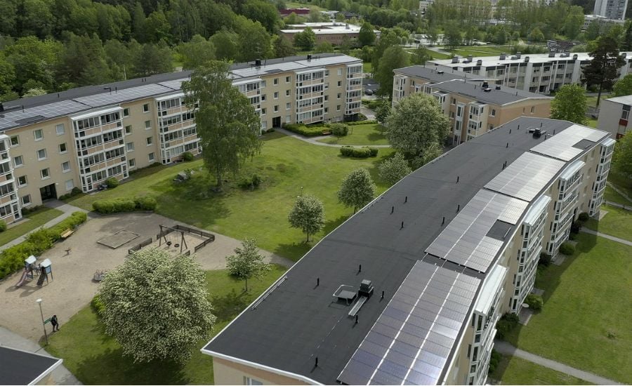 Bostadsområde med flerfamiljshus, solpaneler på taket, grönområden och lekplats
