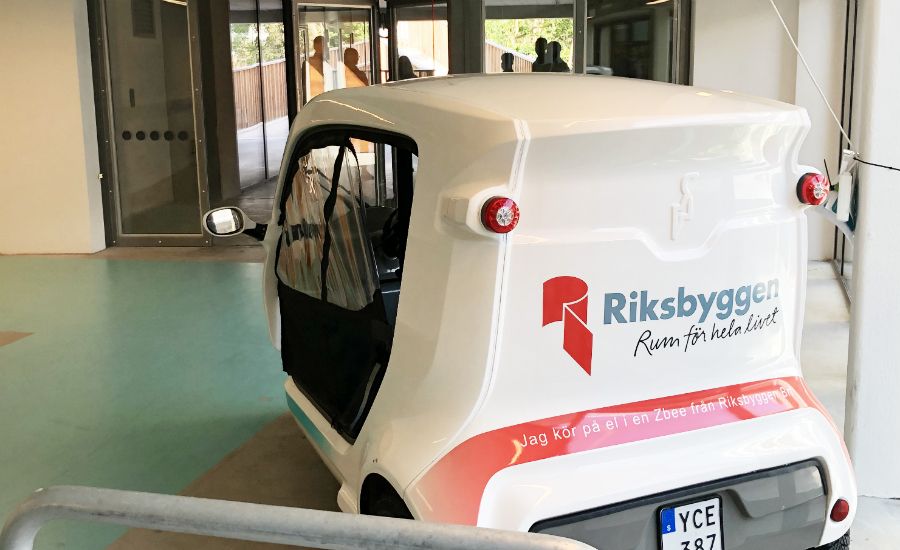 Elbil med logotypen för Riksbyggen parkerad inomhus vid en byggnadsentré