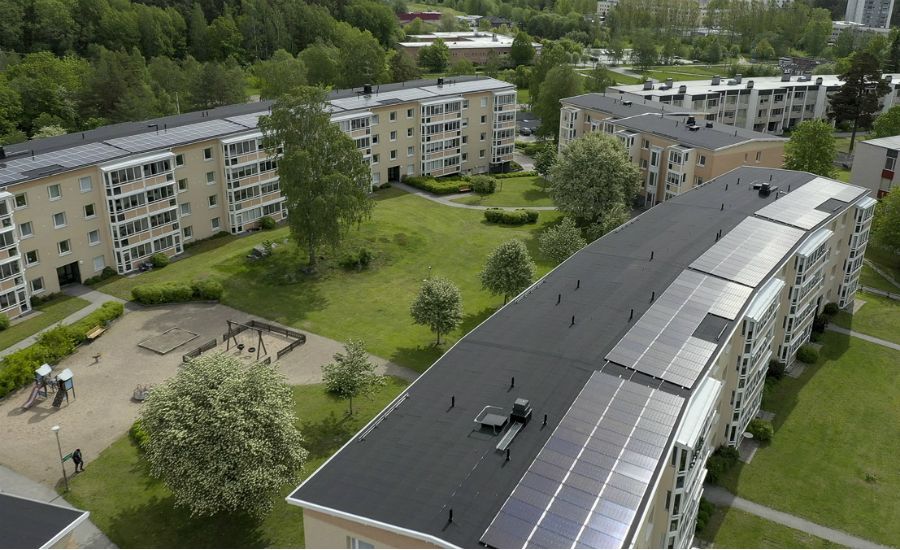 Bostadsområde med flerfamiljshus, solpaneler på taket, grönområden och lekplats