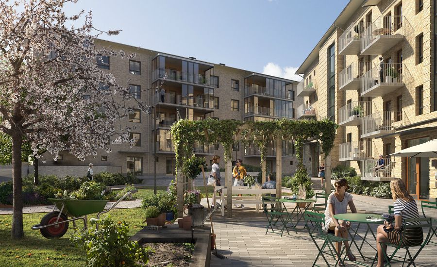 Bostadsområde med moderna flerfamiljshus, gröna uteplatser, blommande träd och människor som kopplar av vid sittplatser