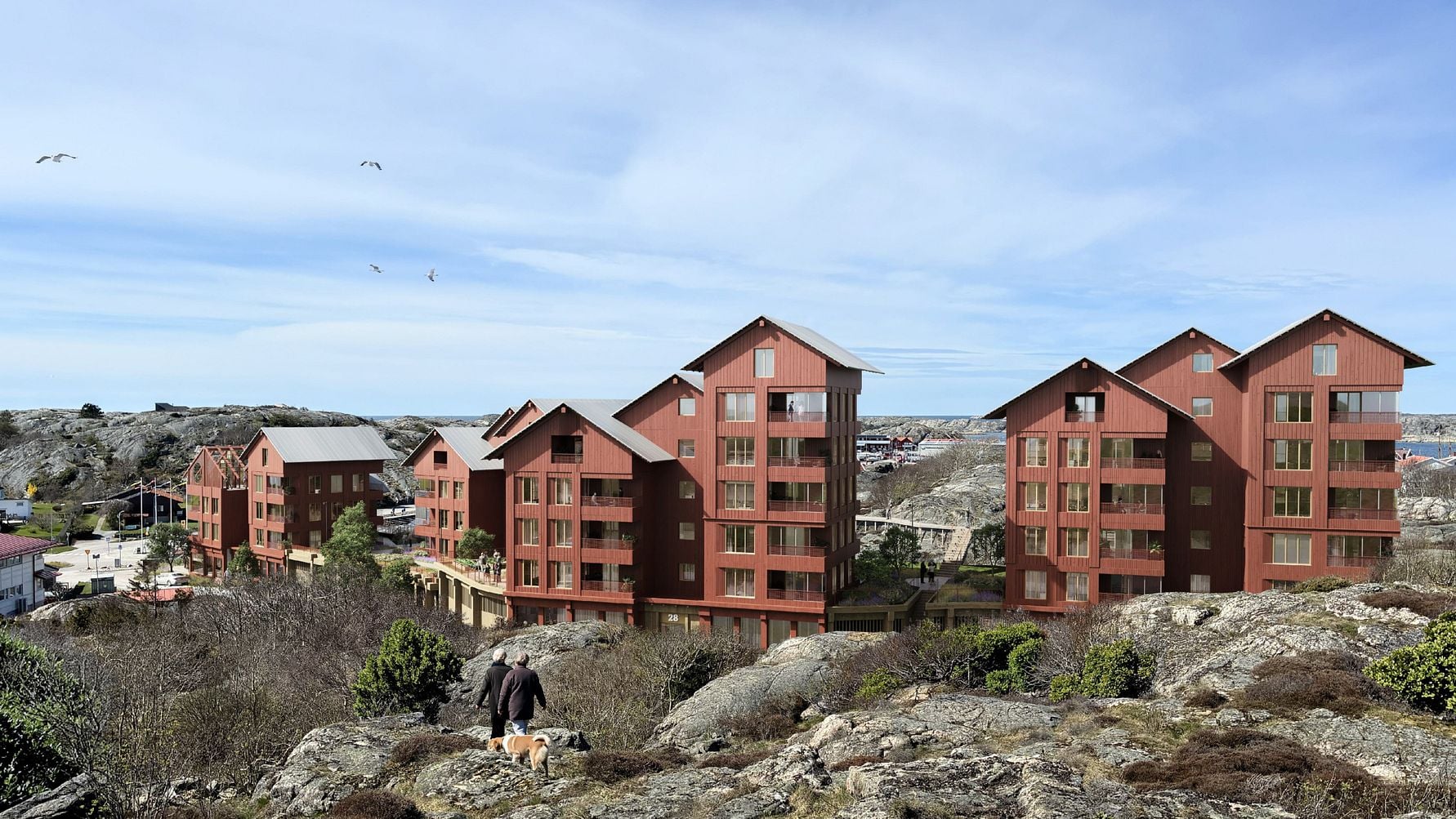 Bostadsområde med röda flerbostadshus vid klippor och hav, med två personer och en hund i förgrunden