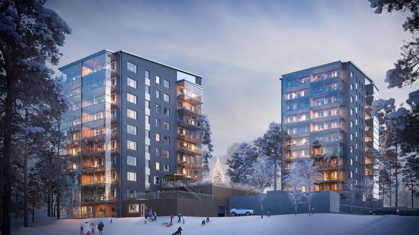 Två moderna flerbostadshus med glasfasader, omgivna av snötäckta träd, med en kvällshimmel i bakgrunden. Snöklädd mark, människor och hundar syns i förgrunden