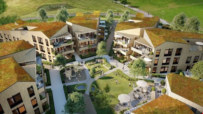 Luftbild av ett modernt bostadsområde med gröna tak, trädgårdar, gångvägar och uteplatser omgivna av grönska