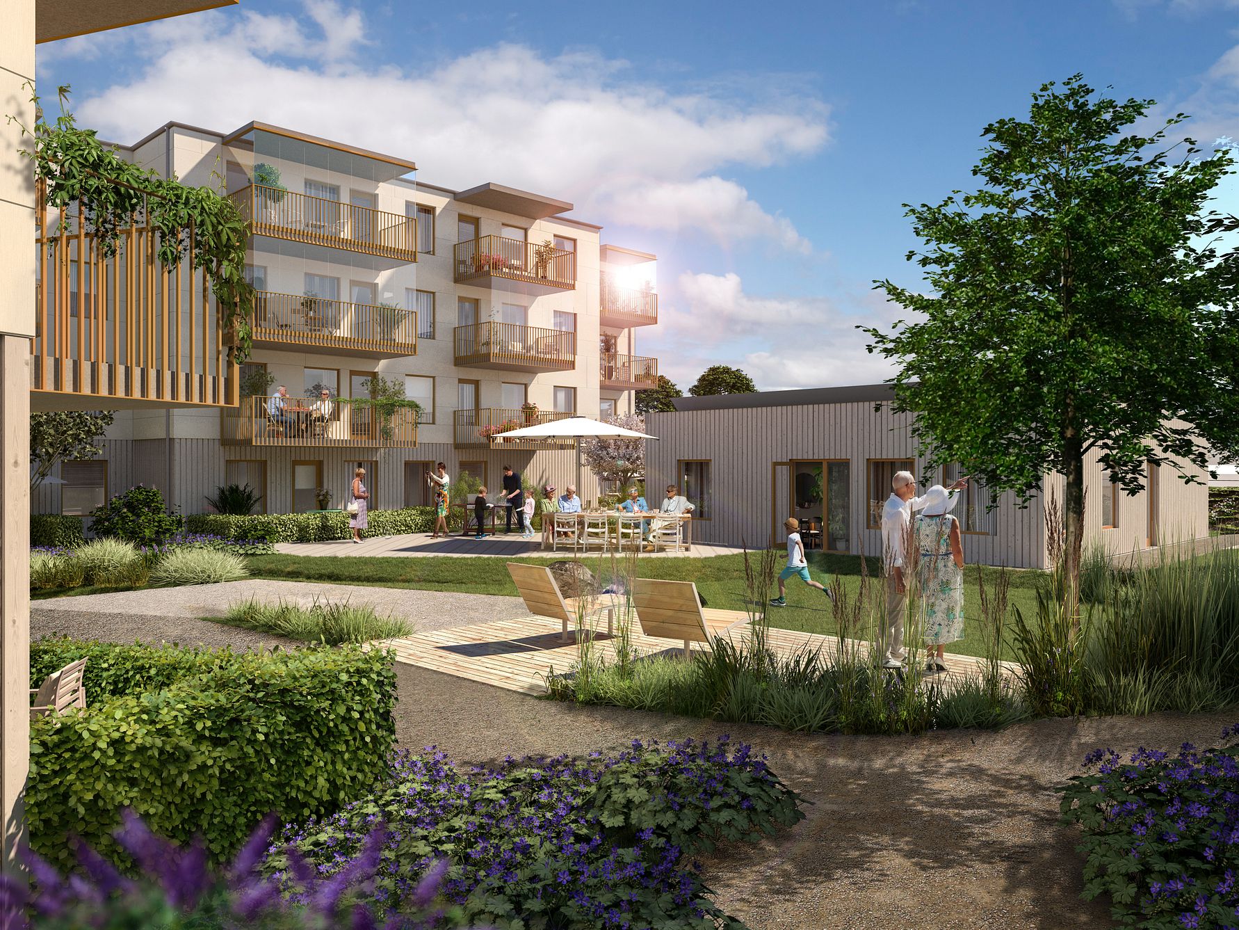 Modernt bostadsområde med flerfamiljshus, trädgårdar och grönskande omgivningar under en klarblå himmel. Människor umgås vid bord och promenerar i området