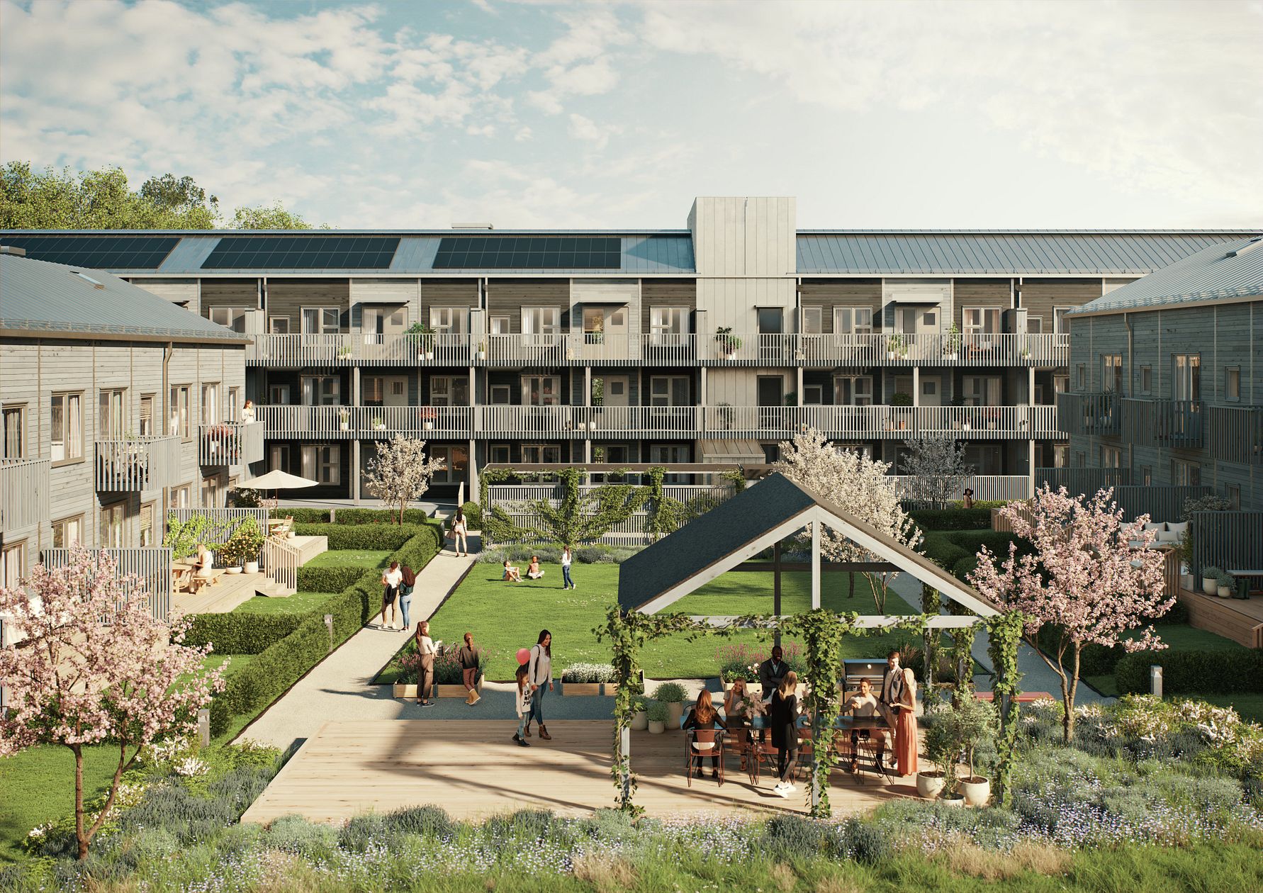 Bostadsområde med moderna lägenhetsbyggnader, grönskande innergård, blommande träd och människor som samlas vid ett bord under en pergola
