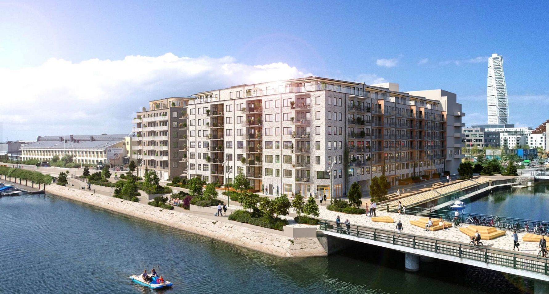 Vy över modern arkitektur vid vattnet, med flerfamiljshus, en bro och en kaj. Turning Torso syns i bakgrunden
