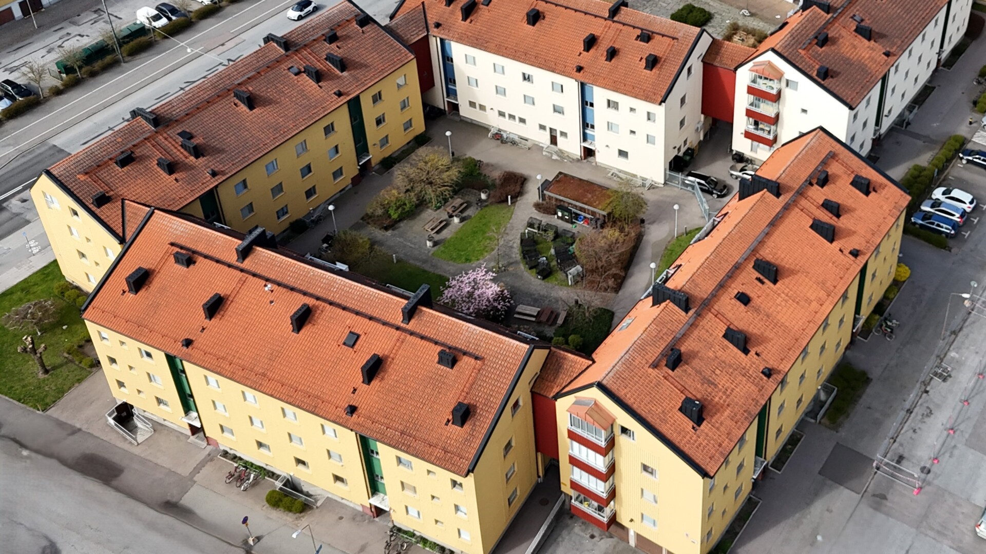 Flygbild av Brf Malmöhus med gula flerbostadshus, röda tak och en innergård