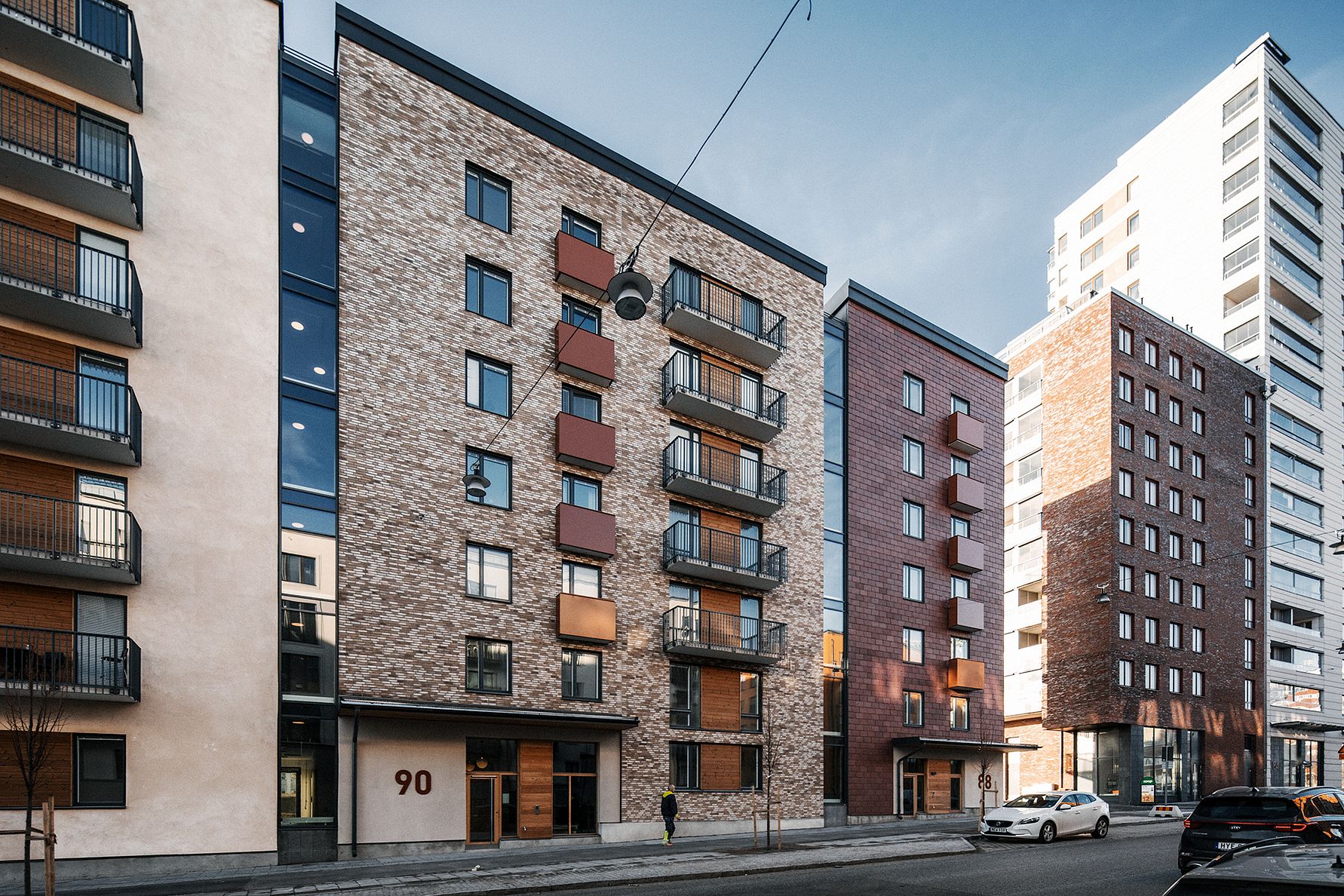 Flerbostadshus med fasader av tegel och glas, balkonger och gatubelysning i en stadsmiljö