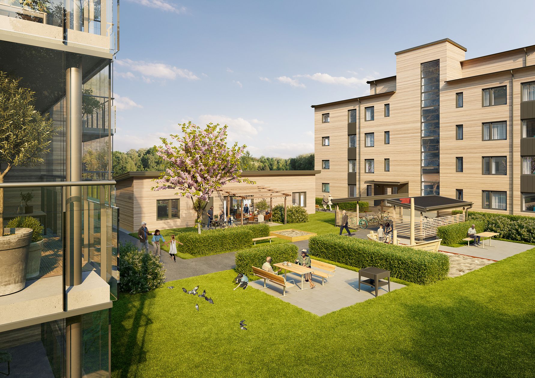 Modern bostadsområde med trädgård, gräsmatta, lekplats och sittplatser. Bakgrunden visar en byggnad med flera våningar och balkonger