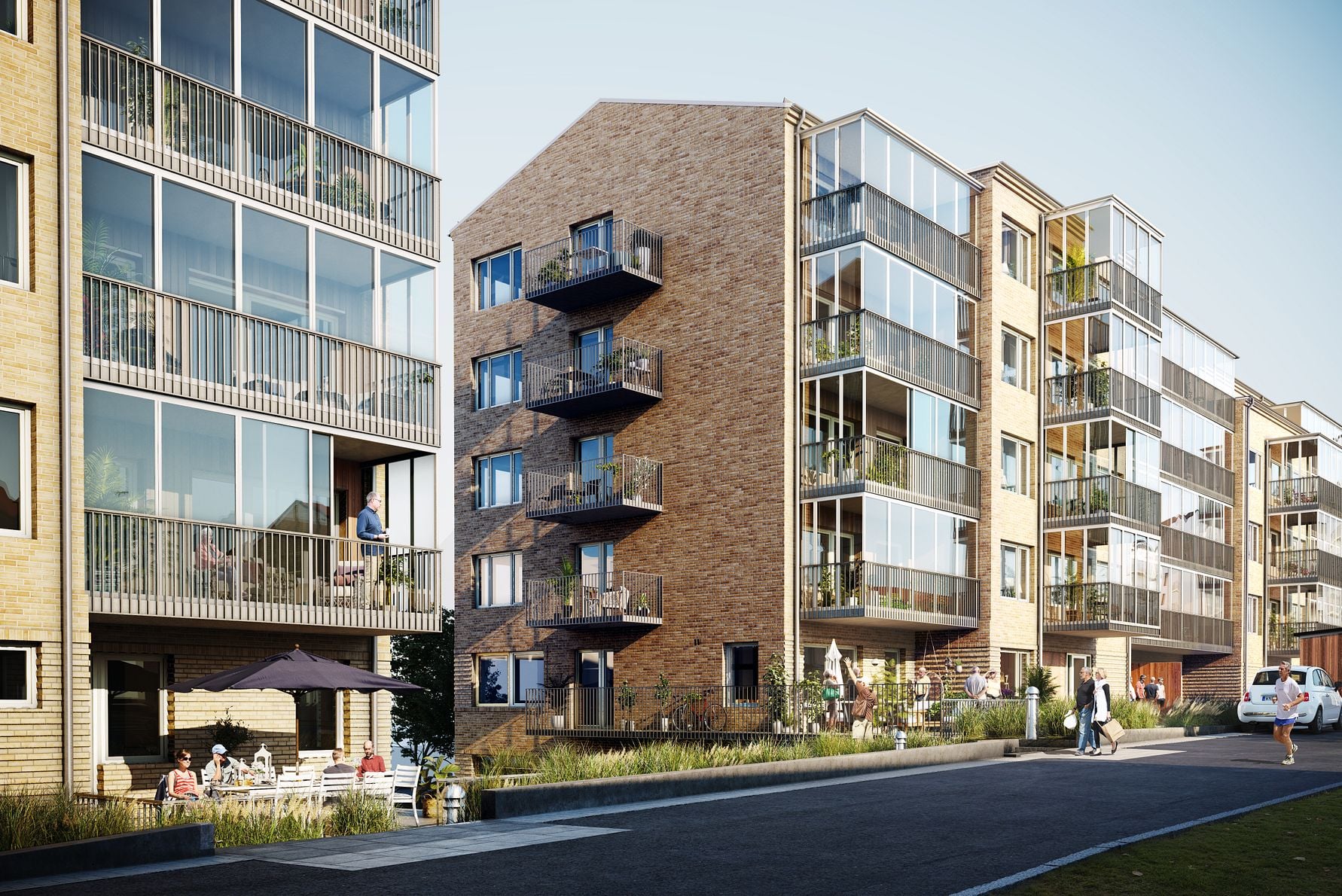 Nybyggda flerfamiljshus med fasader av tegel och glas, omgivna av grönska och gångväg