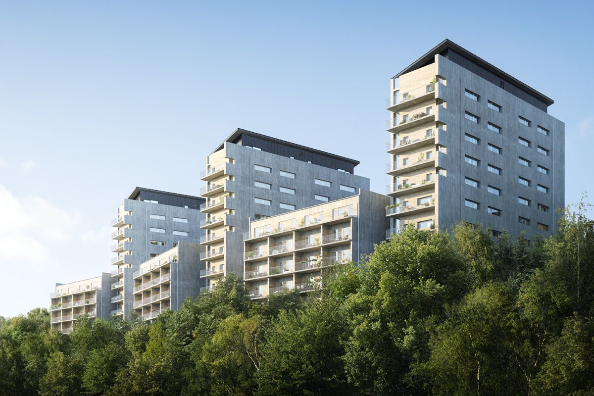 Tre moderna flerbostadshus med grå fasader och stora fönster, omgivna av gröna träd under en klarblå himmel