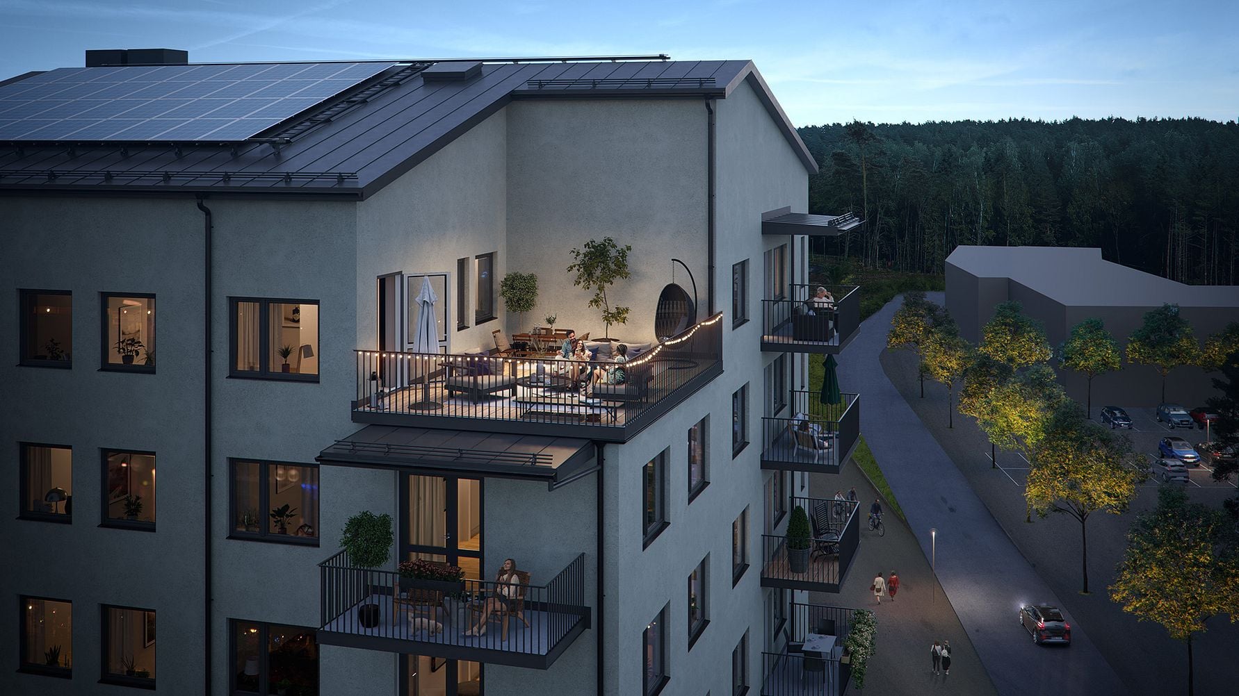 Flerbostadshus med moderna balkonger, solpaneler på taket och belysning, omgiven av grönska och en väg