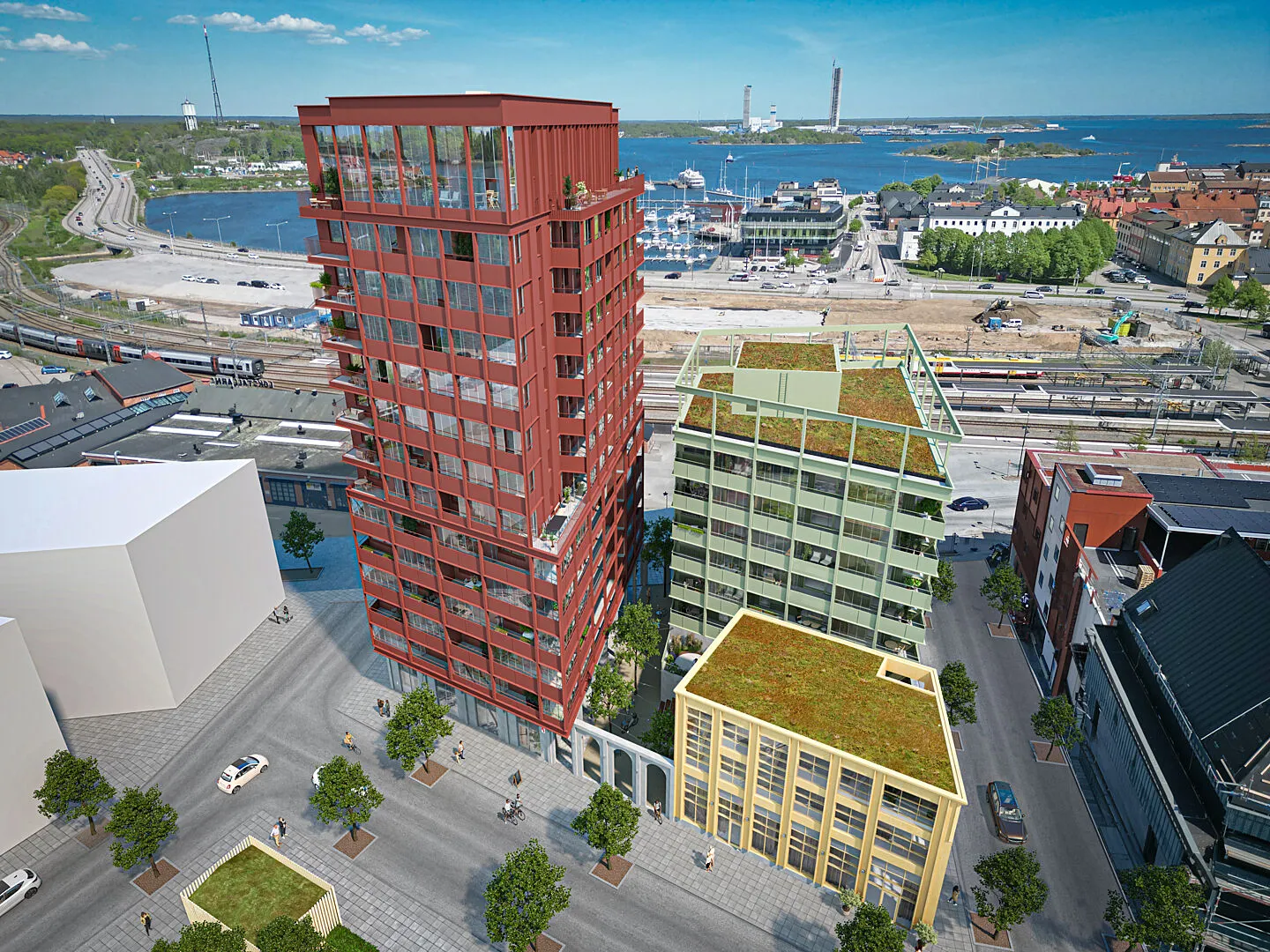 Flygvy över moderna flerbostadshus vid hamnen med gröna tak och stadsmiljö