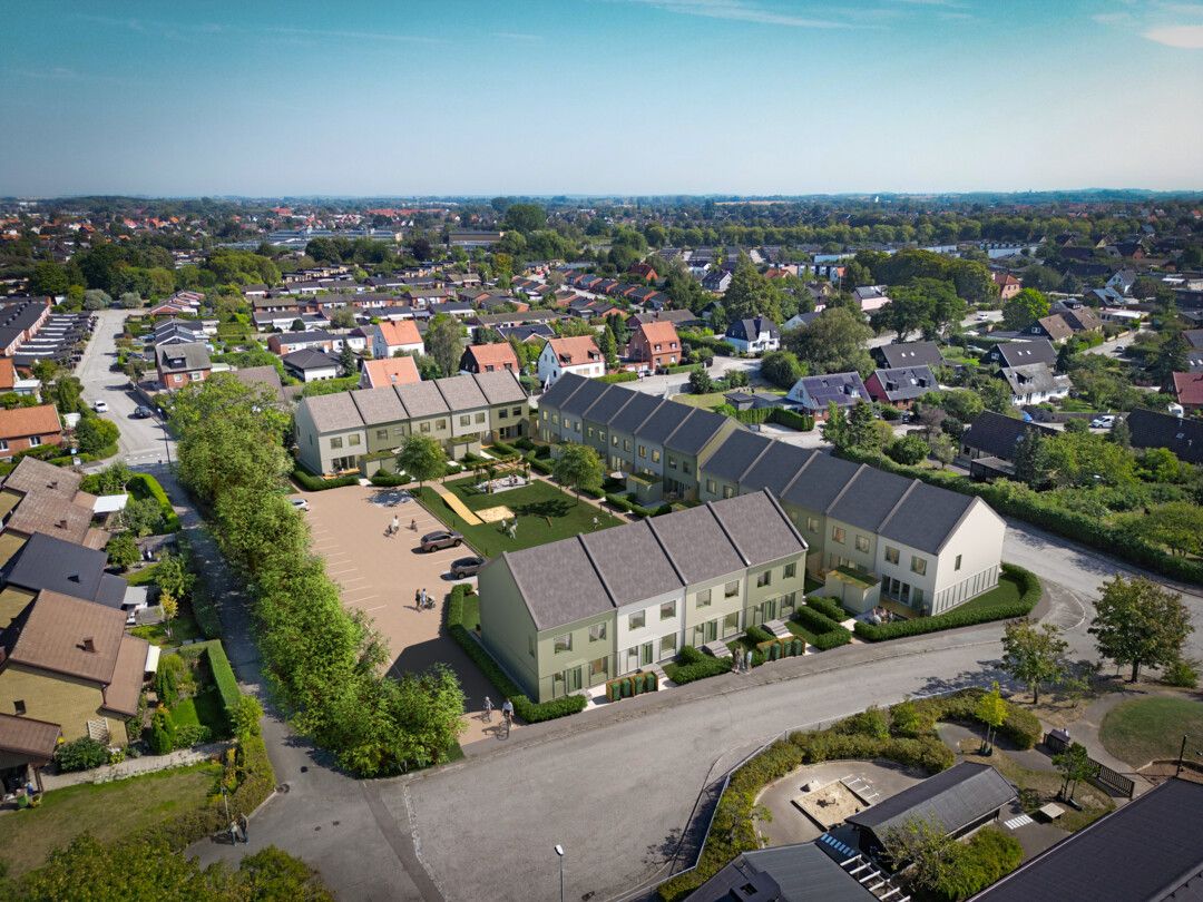 Flygbild över ett bostadsområde med radhus omgivna av grönska och gator