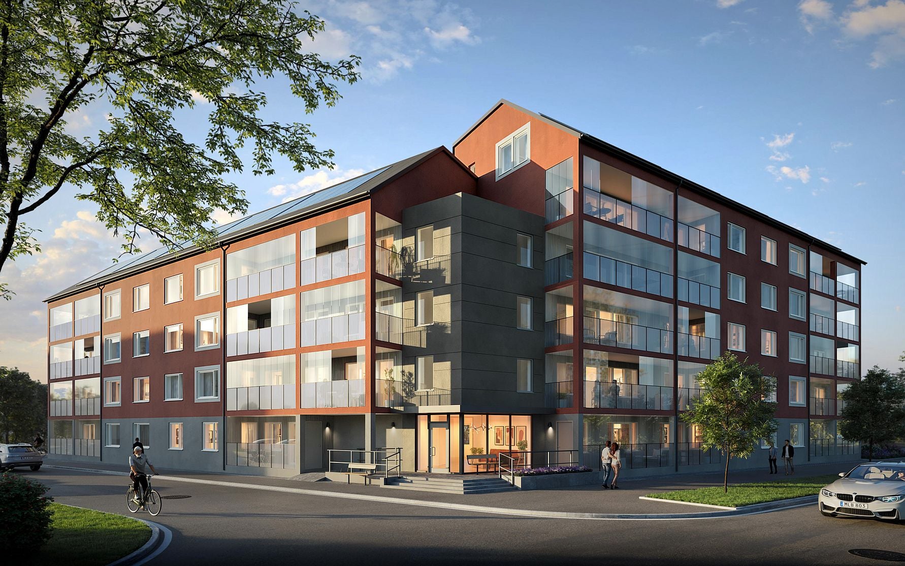 Lägenhetsbyggnad med fyra våningar, stora fönster och balkonger, omgiven av cyklister, gående och gröna träd under blå himmel