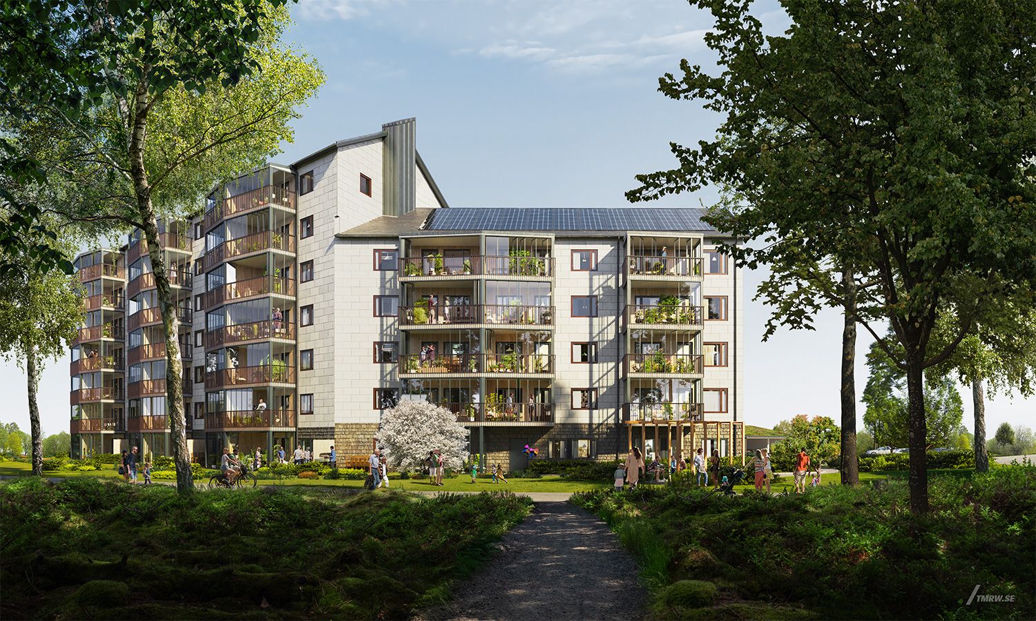 Modern flerfamiljshus med balkonger, omgivna av grönska och träd, med en bred gångväg i förgrunden
