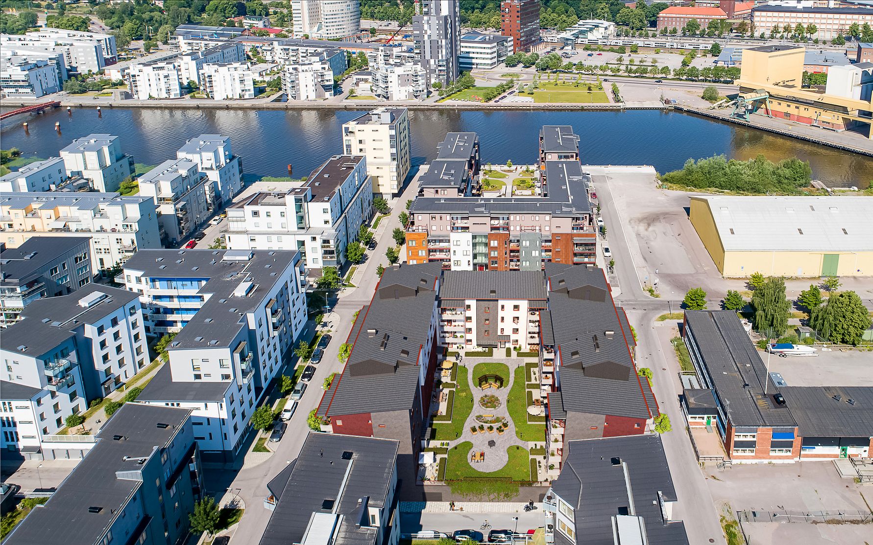 Flygfoto över ett modernt bostadsområde med flerfamiljshus, innergårdar och omgivande stadsmiljö nära ett vattendrag
