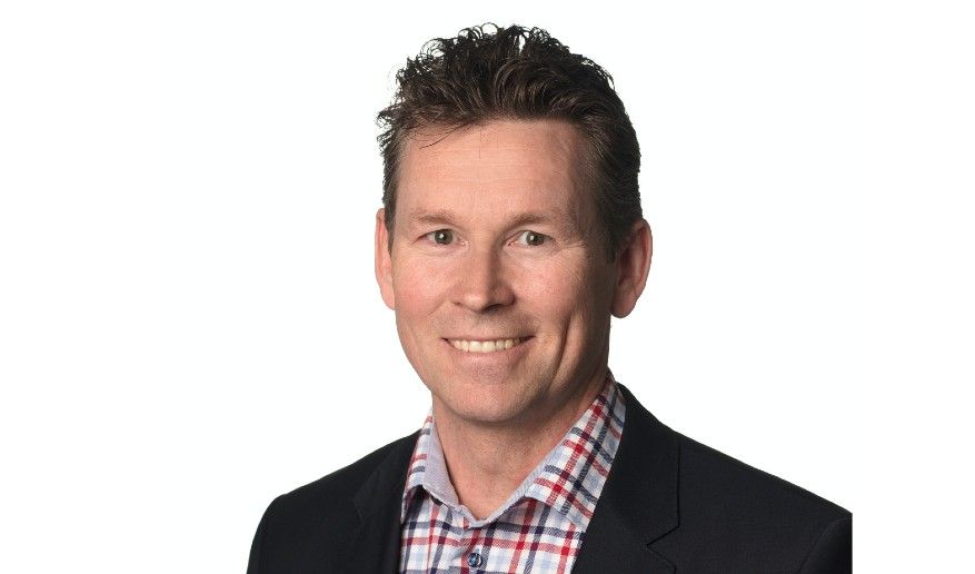 Man i svart kavaj och rutig skjorta mot vit bakgrund