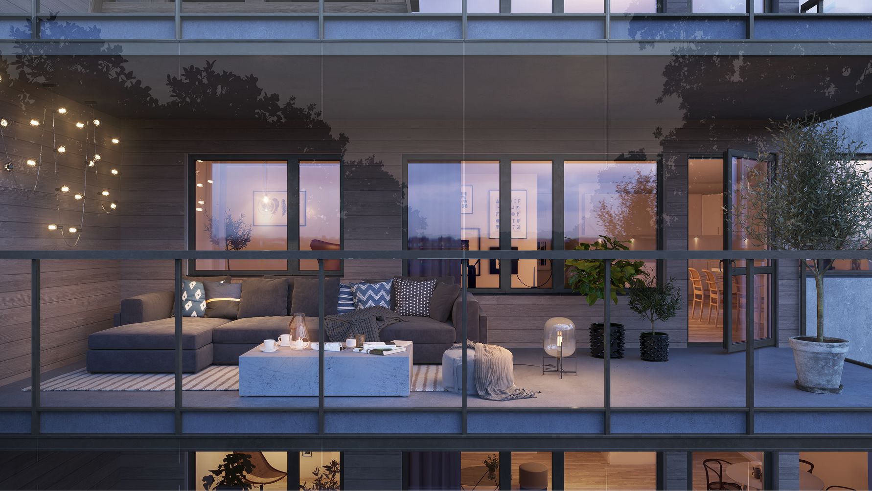 Lägenhetsbalkong med modern inredning, inklusive en grå soffa, ett soffbord och dekorativa ljus, omgiven av glasräcken och träd