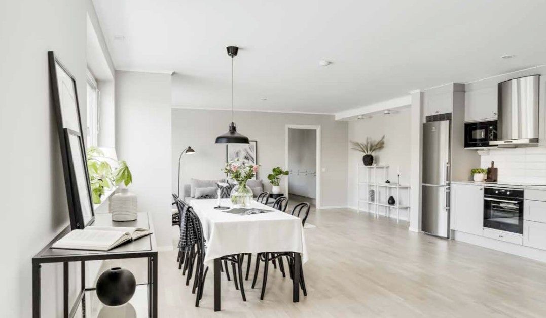 Ljust och modernt kök och matrum med matbord och stolar, vägglampor, växter och öppen planlösning