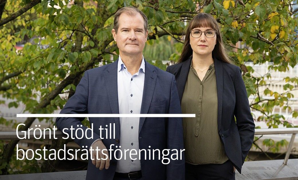 Två personer i formella kläder står framför ett grönskande träd, med texten "Grönt stöd till bostadsrättsföreningar" i förgrunden