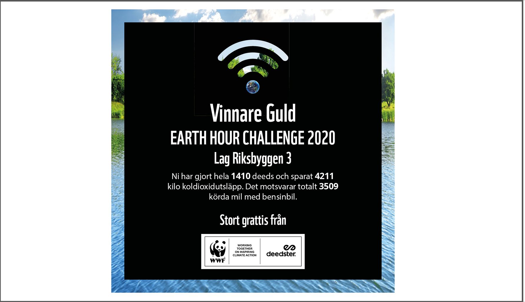 Svart skylt med texten "Vinnare Guld Earth Hour Challenge 2020 Lag Riksbyggen 3," omgiven av natur med vatten och gräsmatta i bakgrunden