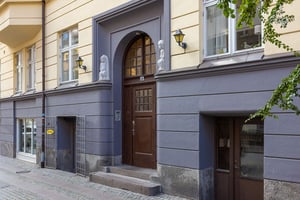 Entré till en byggnad med gul fasad och grå detaljer, dekorerad med två statyer av lejon vid dörröppningen