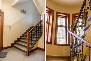 Trappa med räcke i trä och smidesjärn, omgiven av mönstrade glasfönster och väggar i ljus beige färg