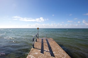 Brygga som sträcker sig ut i havet under en klar blå himmel