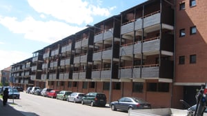 Flerfamiljshus med tegelväggar och balkonger, bilar parkerade längs gatan