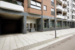 Flerfamiljshus med tegel- och fasadbeklädnad, entréer och fönster samt en gångväg med stenbeläggning framför byggnaden