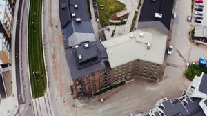 Flygbild av flerbostadshus med omgivande gator, trottoarer och grönytor