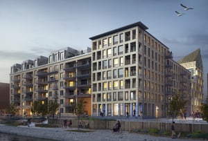 Flerbostadshus vid vattnet i skymningsljus med upplysta fönster, gångväg och människor i förgrunden