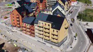 Flera flerbostadshus i nybyggt område med gator, trottoarer och pågående byggarbete