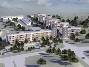 Flera flerfamiljshus med färgglada fasader omgivna av grönska och parkeringsplatser, sett från ovan