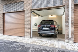 Bil parkerad i en öppen garageport med tegelväggar och omliggande garageportar